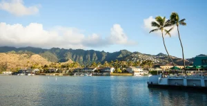 Landscape shot with water in the foreground, residential areas, and mountains in the background