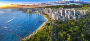 An aerial shot of Honolulu, including the ocean, beach, and mountains in the background